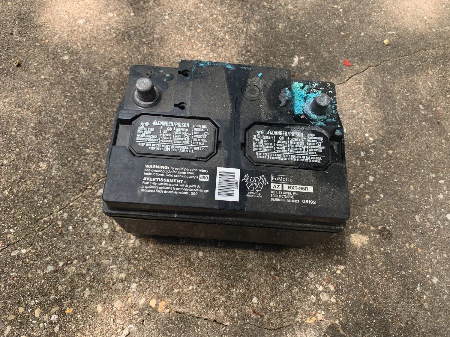 Picture of a car battery that has visable blue corrosion on the negetive terminal.
