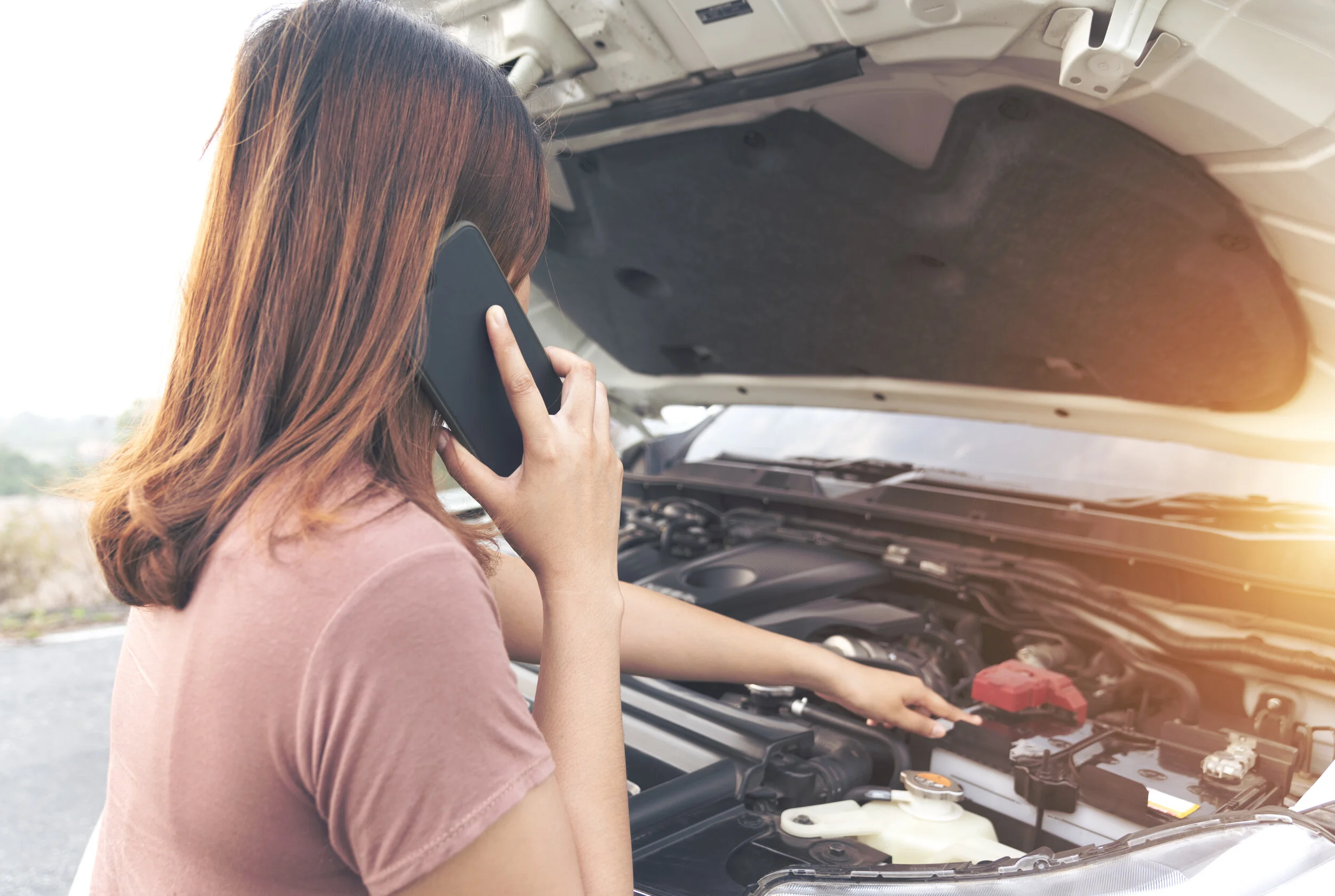 Girl near a broken car on the country road is calling