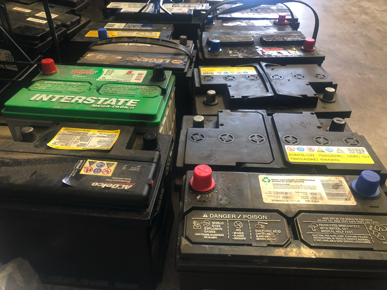 Numerous bad car batteries lined up next to one another.
