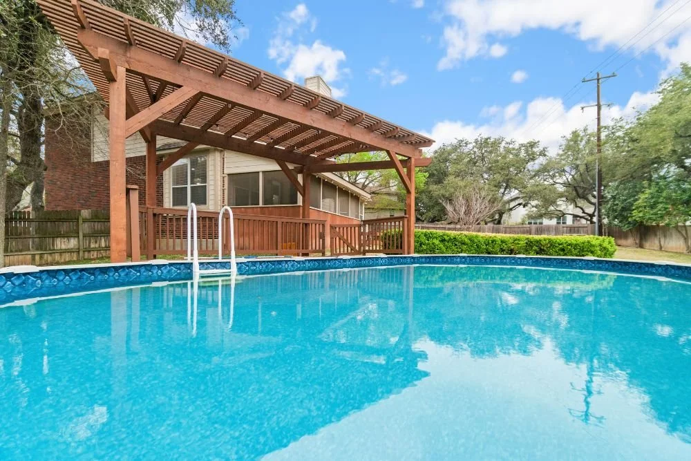 Backyard swimming pool beside a wooden pergola and deck