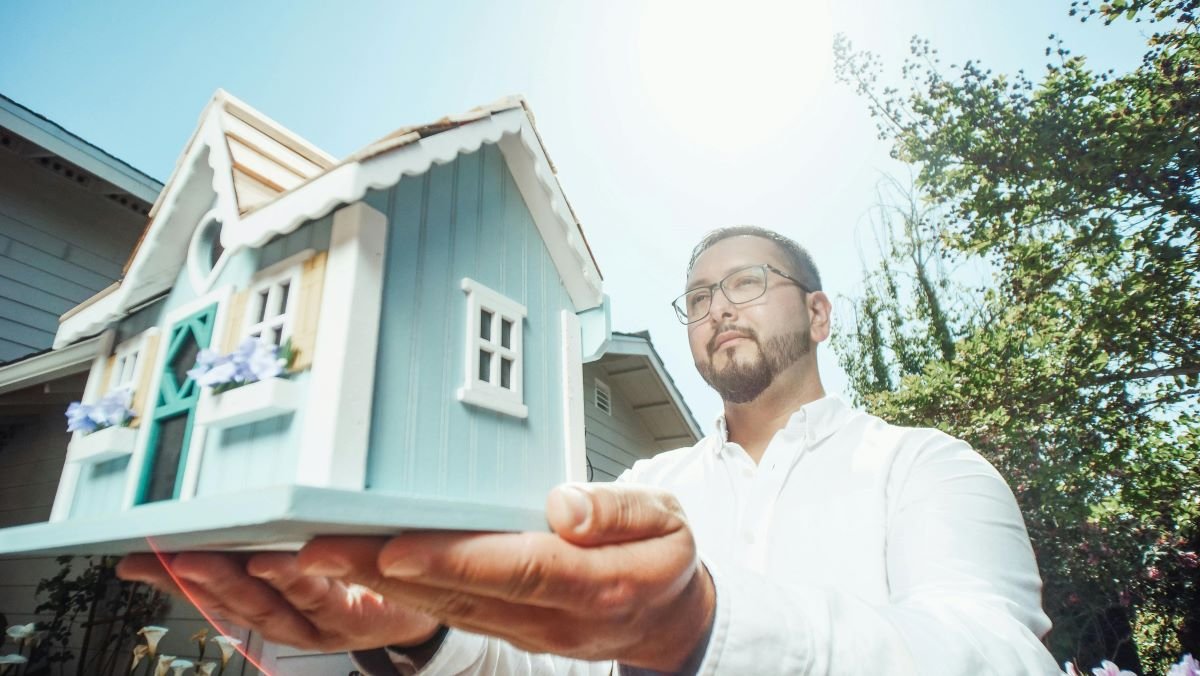 Person holding a model house outdoors, illustrating how emotional buying decisions spike during relocation periods.