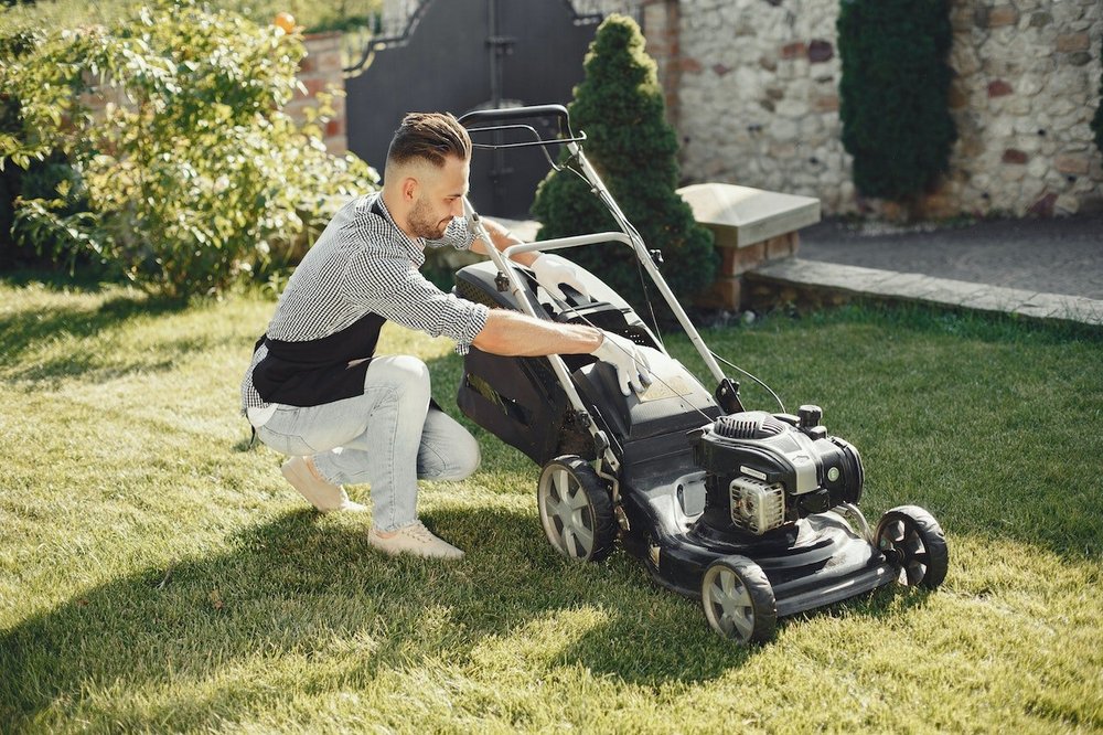 : A man working with a land mower in the backyard