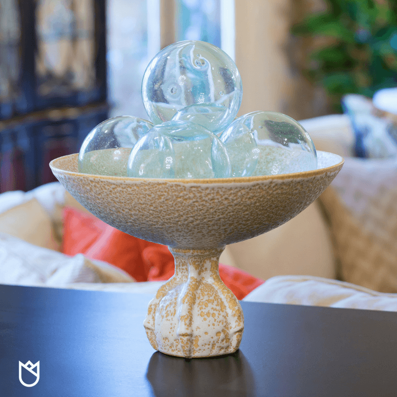 A claw foot urn filled with glass balls looks perfect on this sofa table