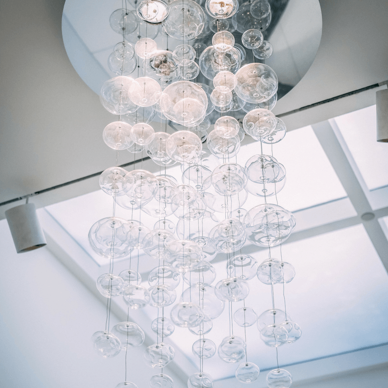 We like to define the dining room with a large chandelier or pendant. Look for one with distinct layers of lighting. Place this light fixture over a big chunky dining room table with up