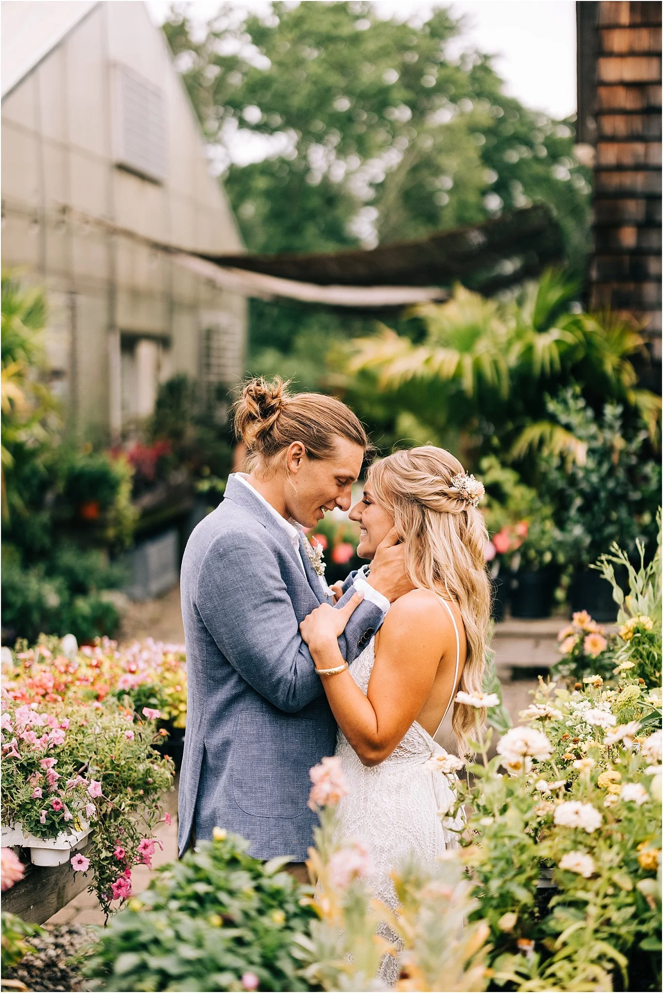 A bride and groom embrace each other in a garden of colorful flowers, smiling and gazing into each other's eyes during their wedding.