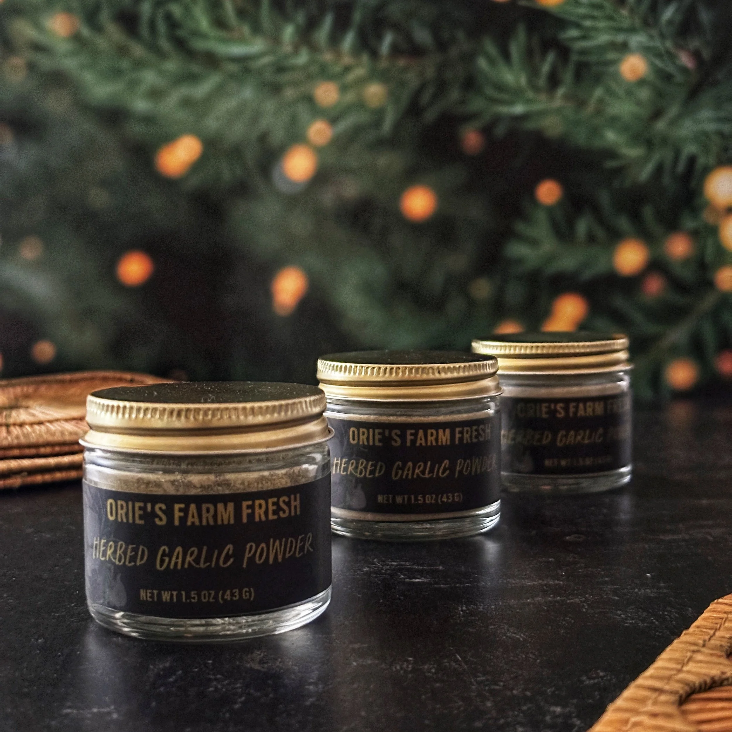 Three jars of Herbed Garlic Powder are arranged diagonally across the frame on a slate surface.