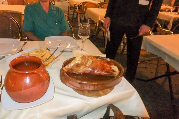 Having the specialty of Segovia, roast suckling pig. Note that the waiter is about to cut the pig with a dish.