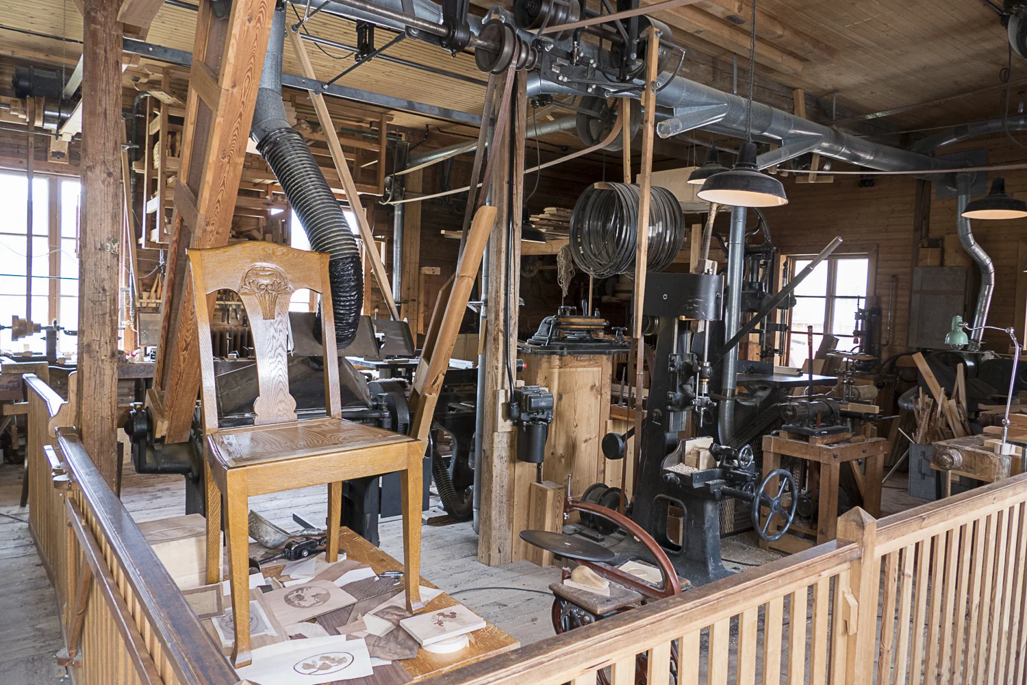 Woodworker’s shop with all of the machinery running off a system of belts at the ceiling.