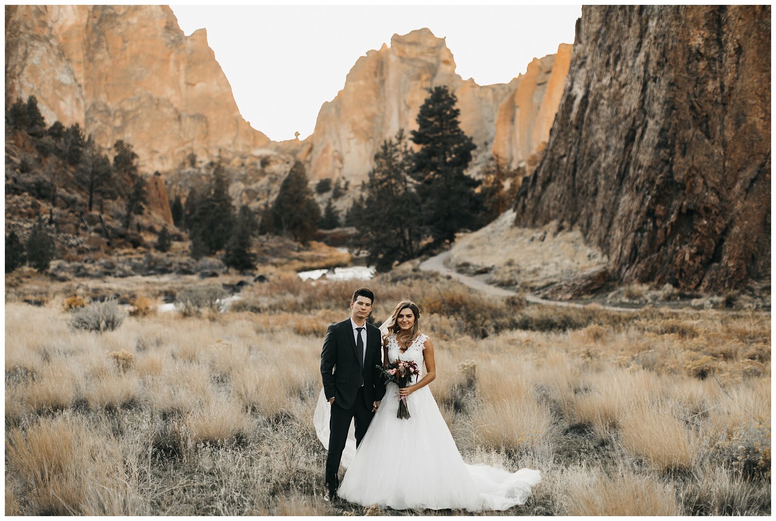  Smith Rock Day After Wedding Photo Session dramatic Oregon wedding photo location wide frame of bride and groom in sunlit field 