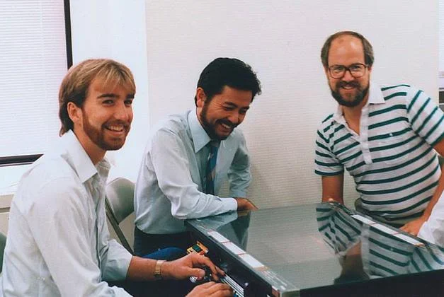 Doug, Scott Tsumura (Irem at the time of photo, now Tozai Games) & Gary Carlston (Brøderbund) with the tabletop arcade version of Lode Runner. Japan 1984.