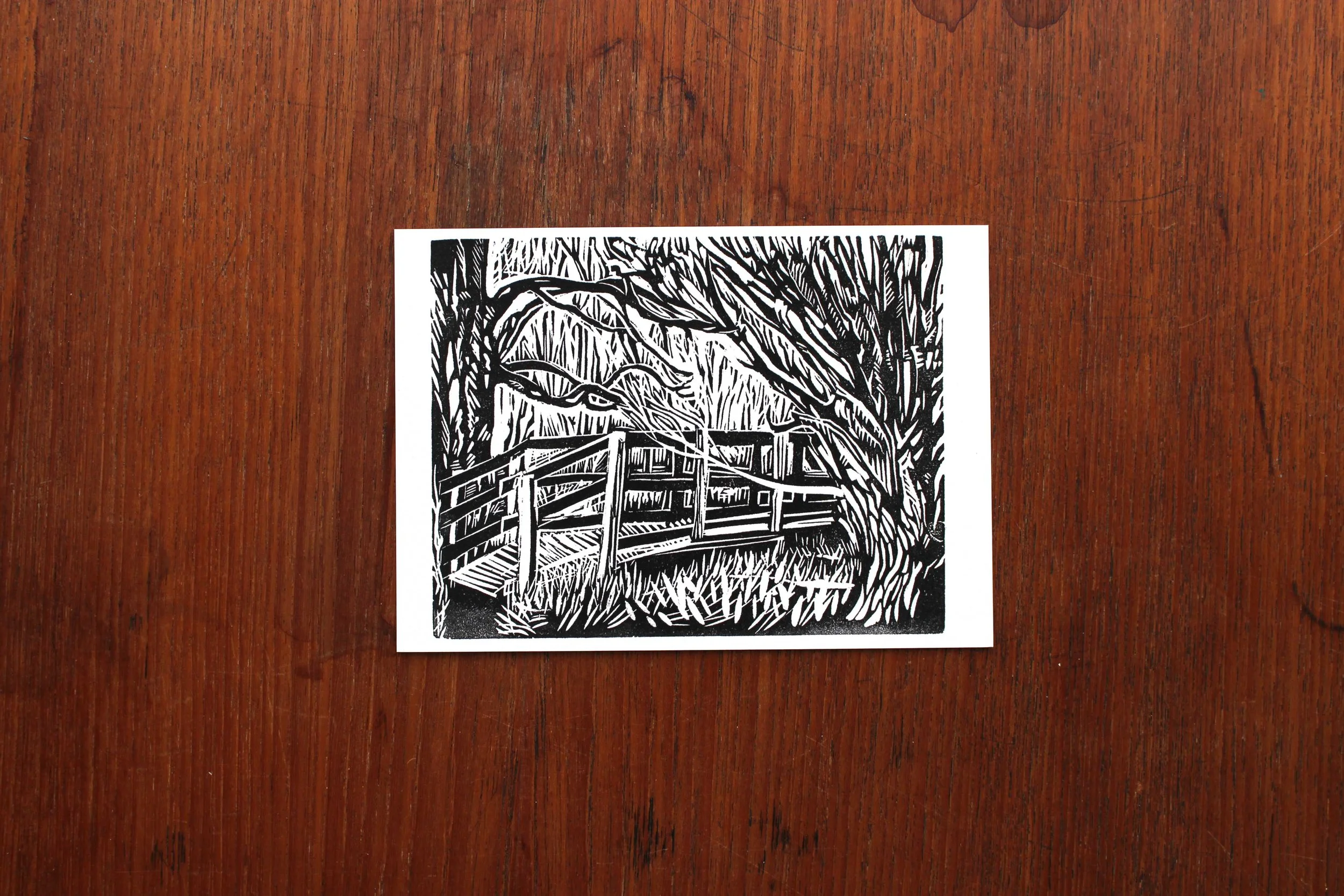 Postcard walk river pooh-sticks bridge linocut print Cat Moore single block trees woodland