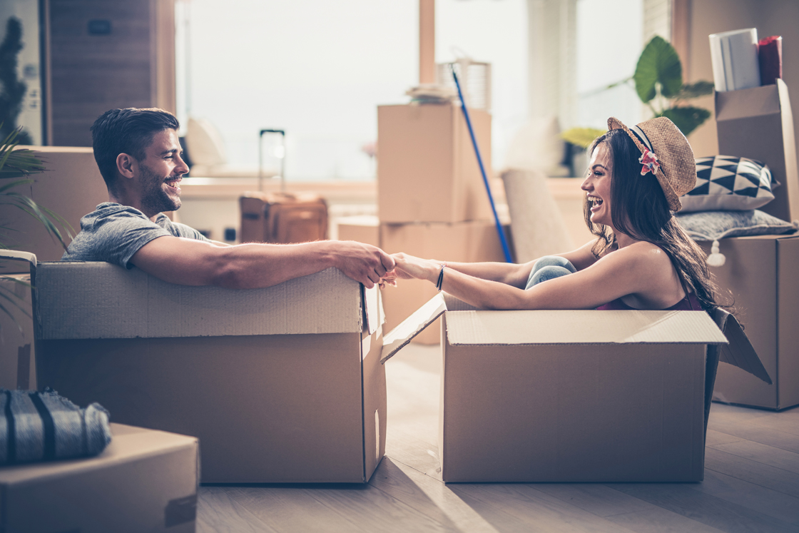Cheerful-couple-having-fun-while-sitting-in-cardboard-boxes-at-their-new-home.-858229452_low.jpg