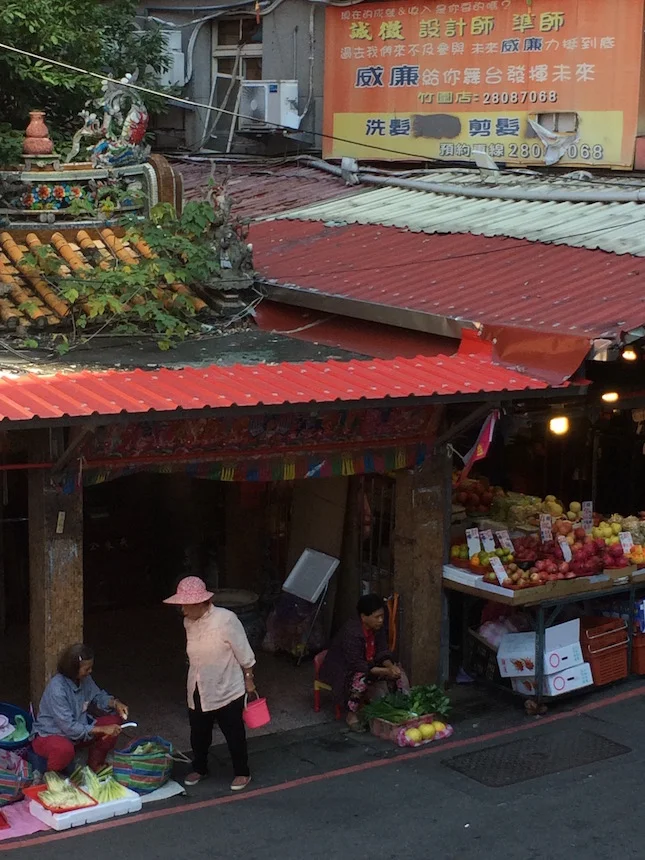 Traditional market-sellers of vegetables, meats, and fruits outside a tiny local temple in nearby Zhuwei
