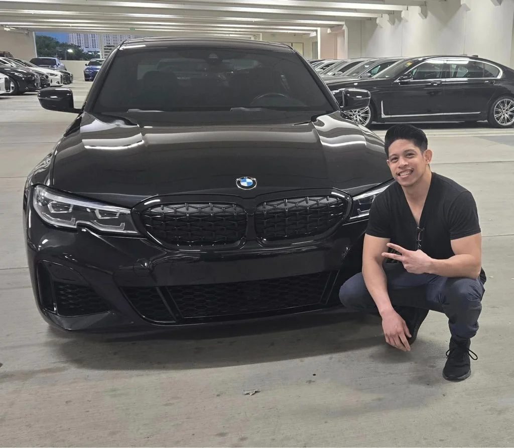 Young man smiling next to his new BMW car