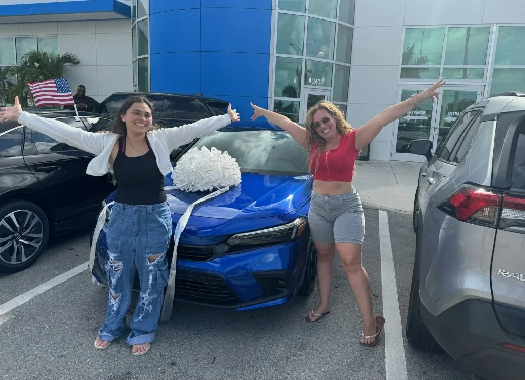 Mother and daughter smiling next to a new car for the daughter