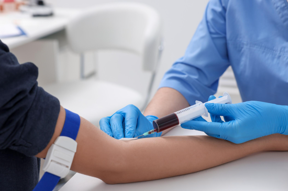 Healthcare professional drawing blood from a patient's arm into a syringe