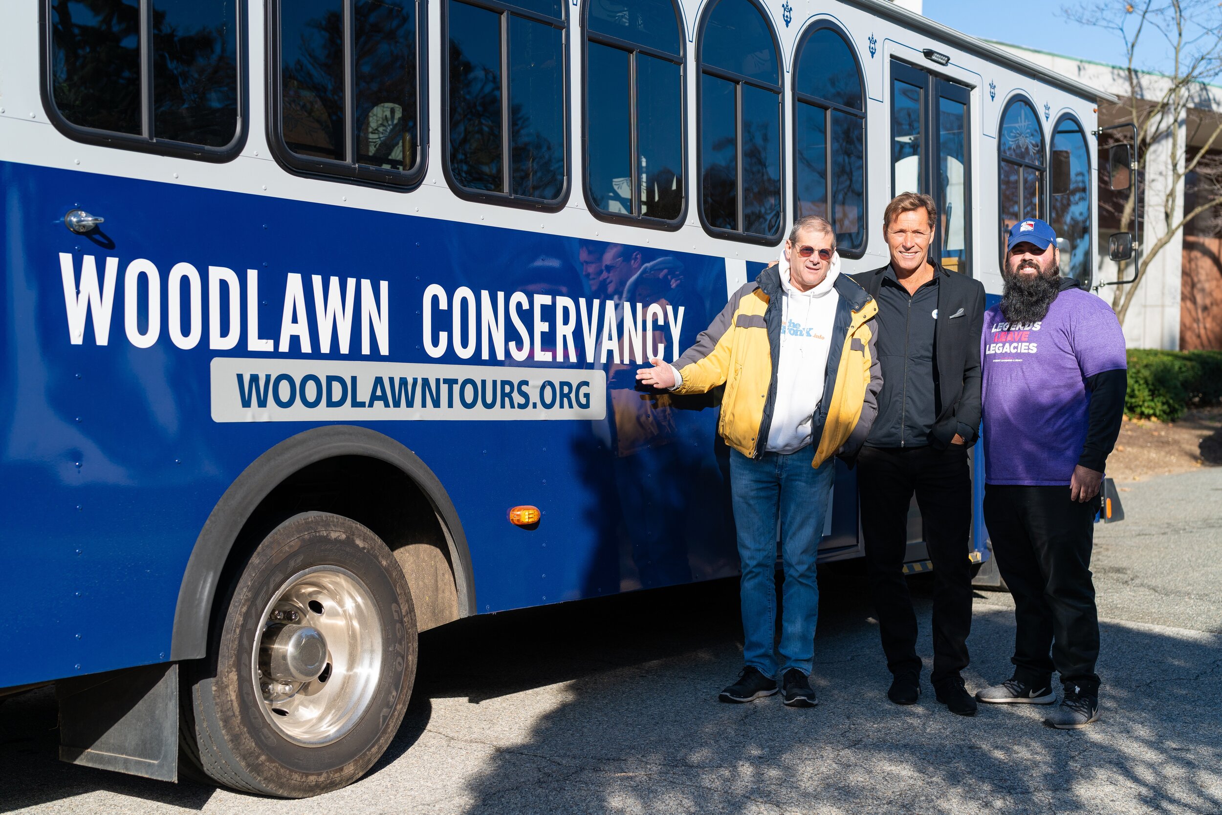   Ron Duguay (center) poses with Woodlawn educator Jordan Fernandez (right) and Gary Axelbank (left) from This is the Bronx, in front of the Woodlawn Cemetery Tour Trolley.  