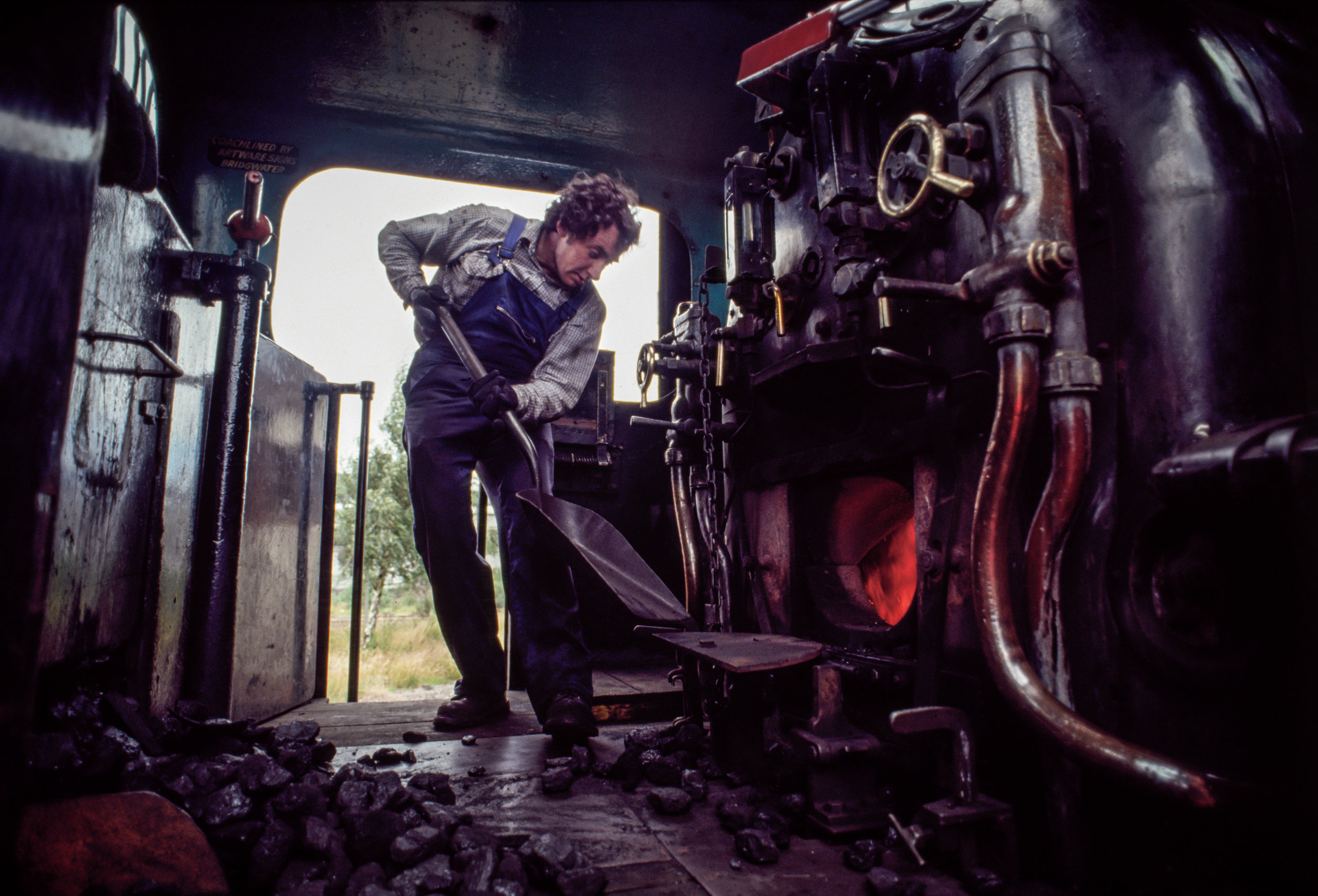 A fireman for the Strathspey Railway shovels coal into the boiler of a locomotive en route from Boat of Garden to Avimore in Scotland