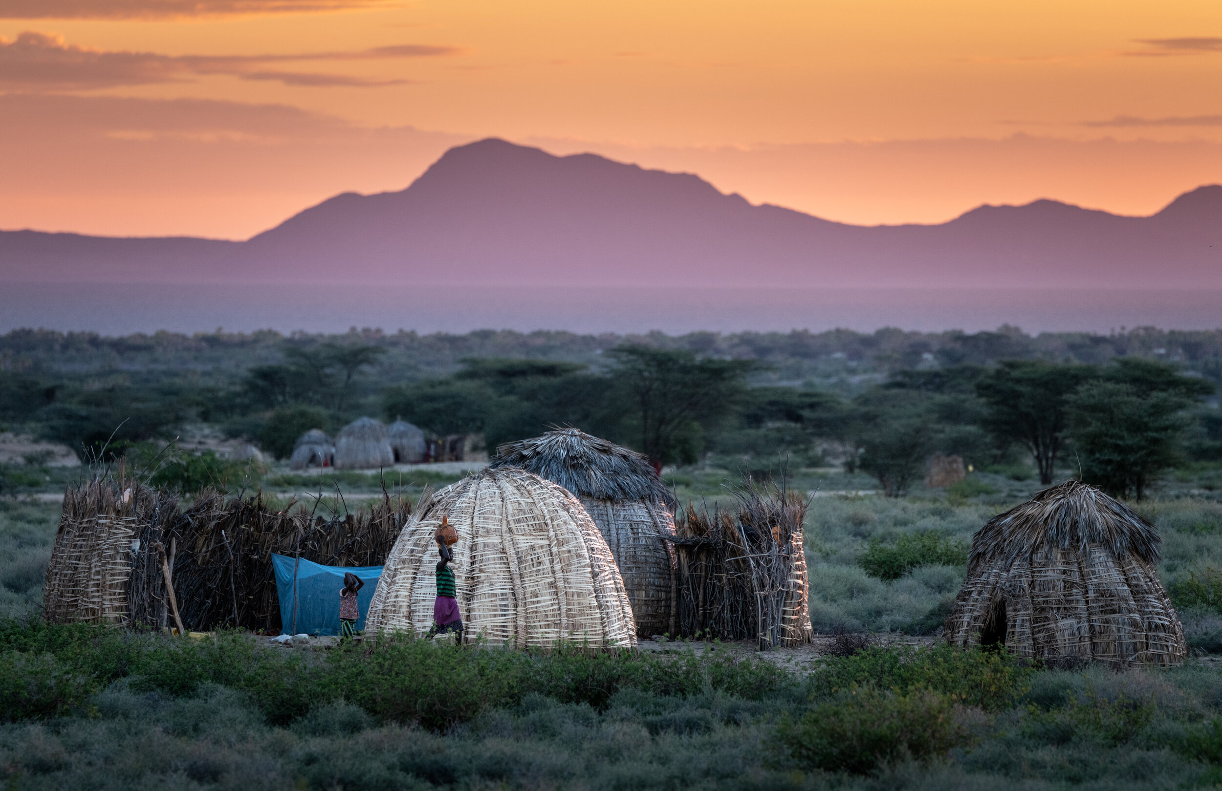 Abei Ekai, left, and Akamais Kai, right, start their day as the sun rises over their family’s home on the shore of Lake Turkana with the Central Island in the background