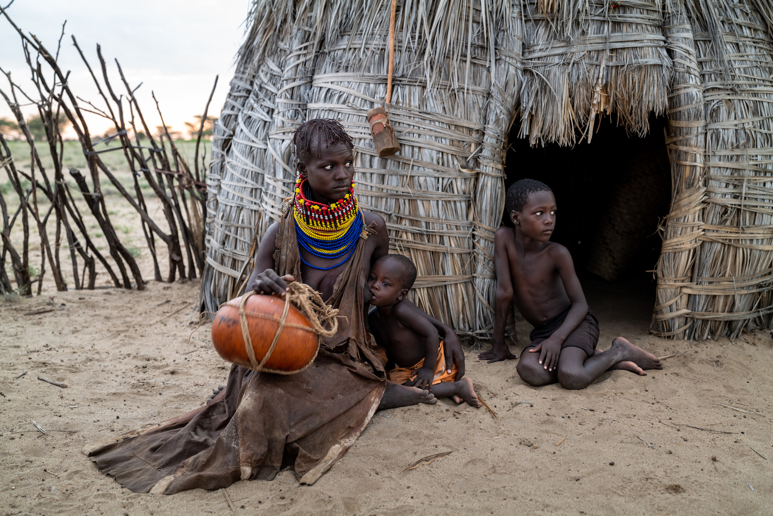 Ayanae Ewar breast feeds Anam Eipa along side Alimlim Ewar at their family’s home on the shore of Lake Turkana in Kenya