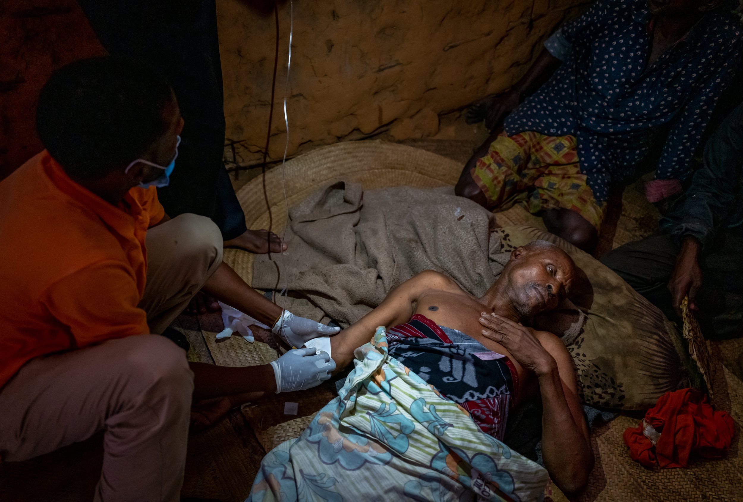 Dr. Athman Vae places an IV in Omar Shongwa in Shongwa’s mud hut in the village of Bahamisi, Kenya