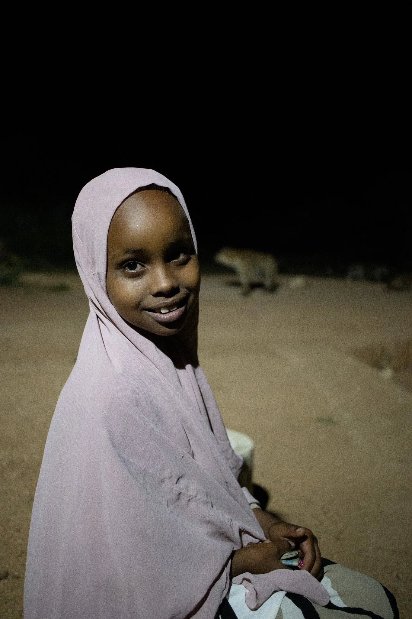  Harar, Ethiopia.   After helping a grandparent prepare meat for the hyenas that descend from the hills each night, the subject paused for a portrait. Delighted by the camera and eager to see the photograph shared, the subject and her grandfather gla