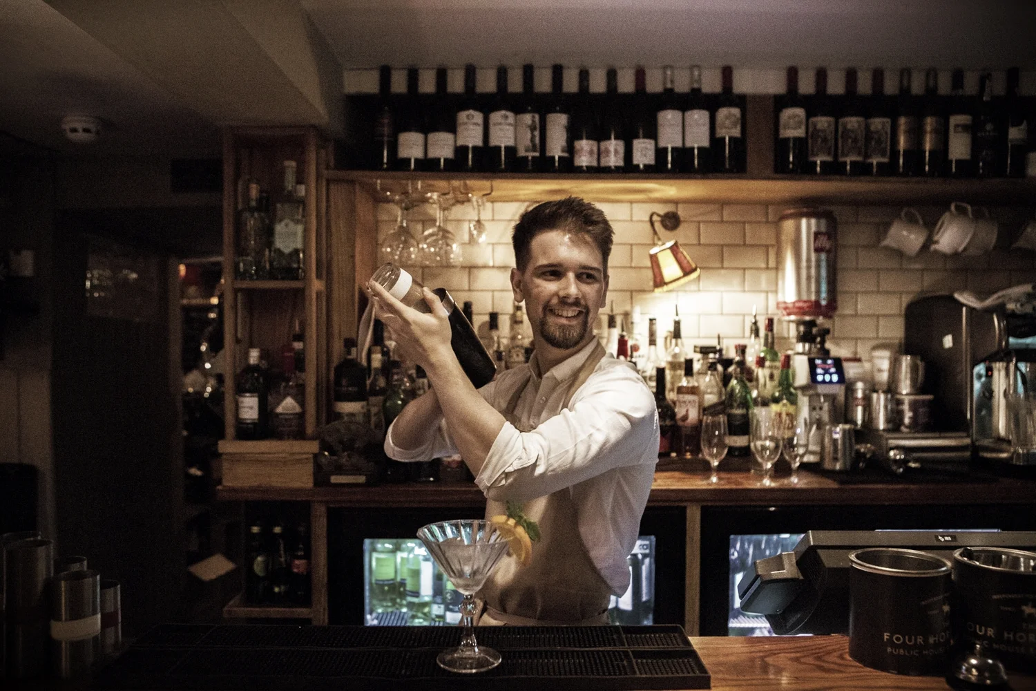A bartender shaking a cocktail behind the bar