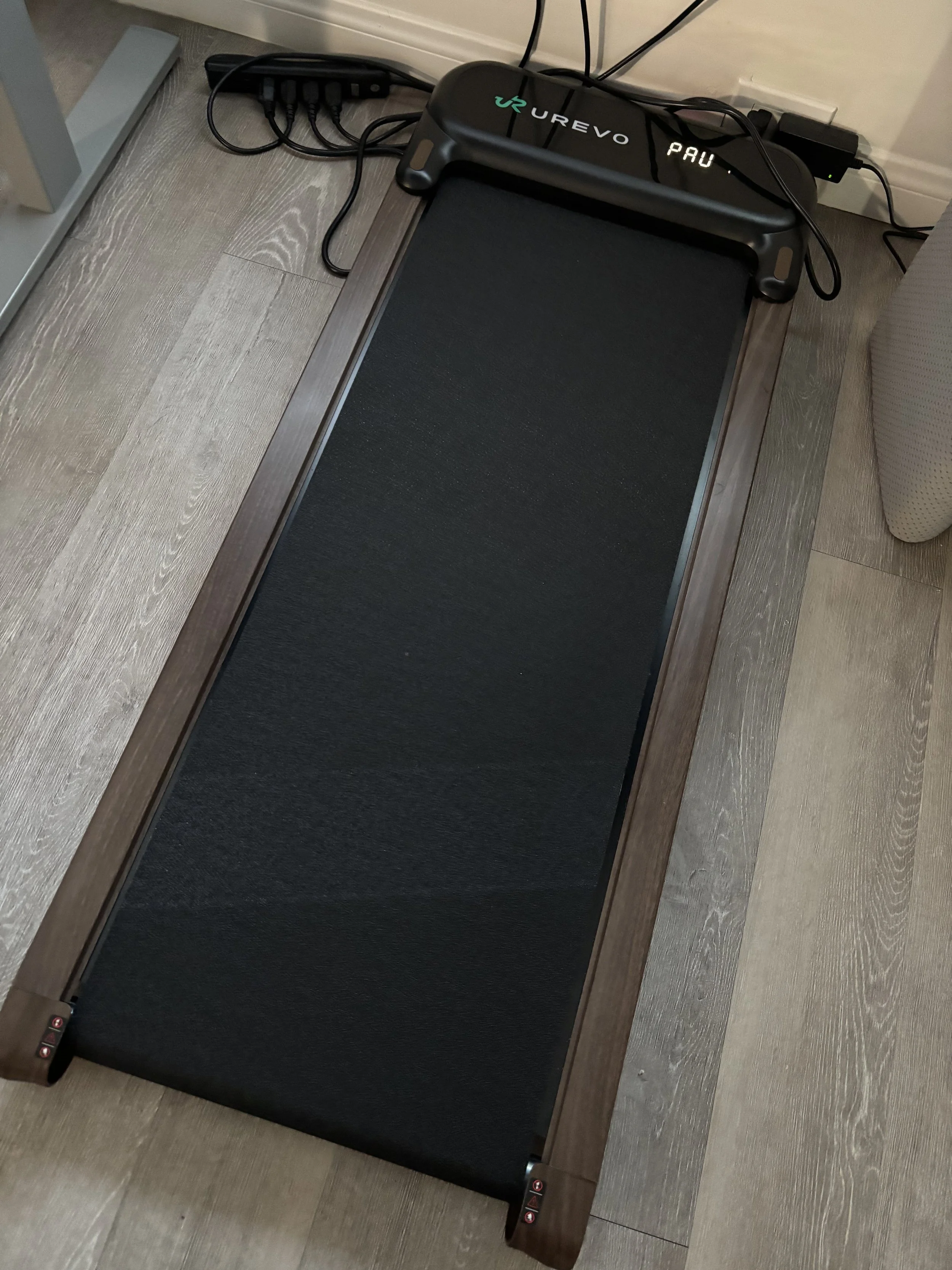 Photo of a walking pad next to a handful of black power cords.