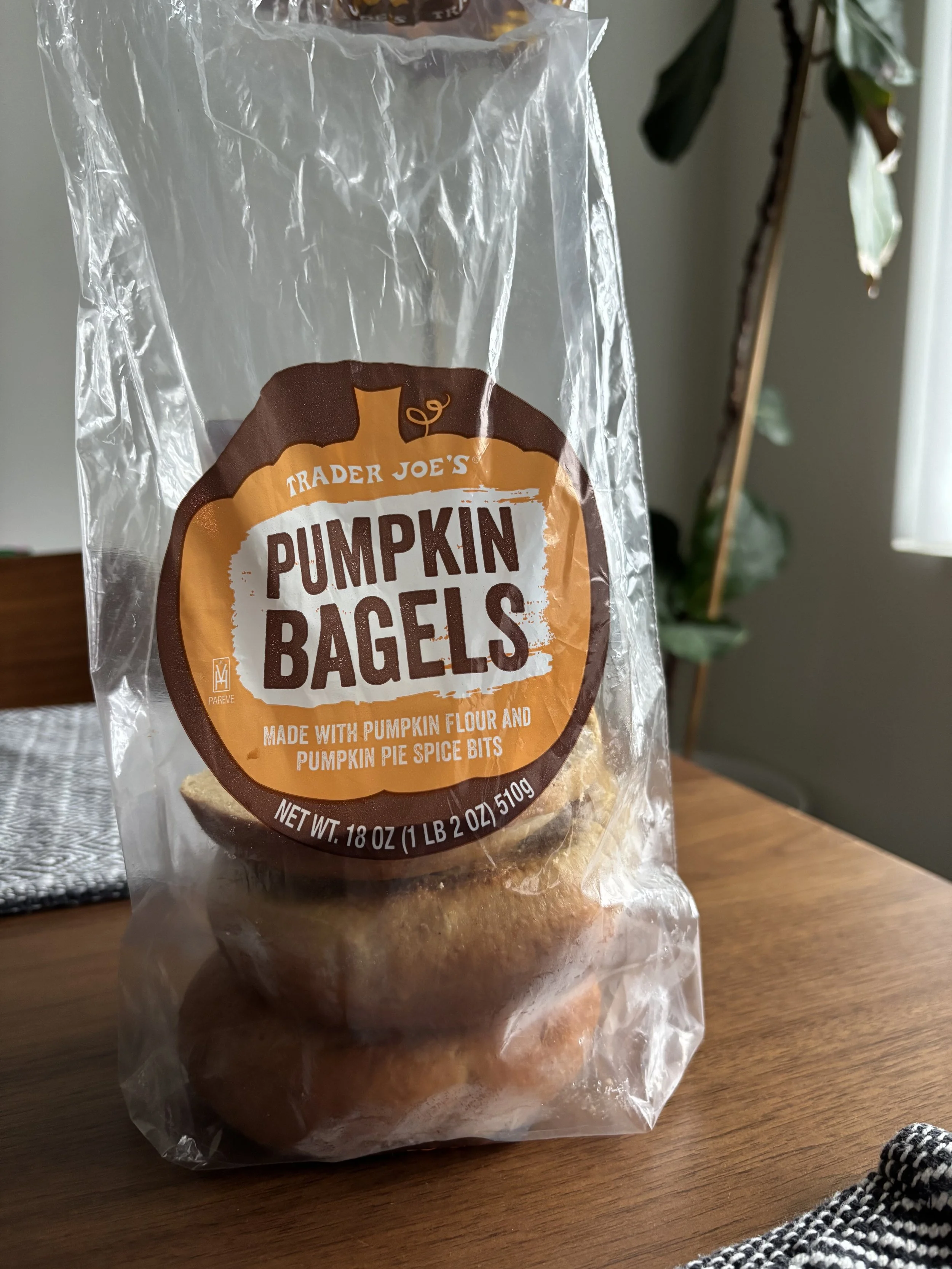 A plastic bag with the label "Trader Joe's Pumpkin Bagels" printed on the front, and two and a half bagels visible inside the bag.