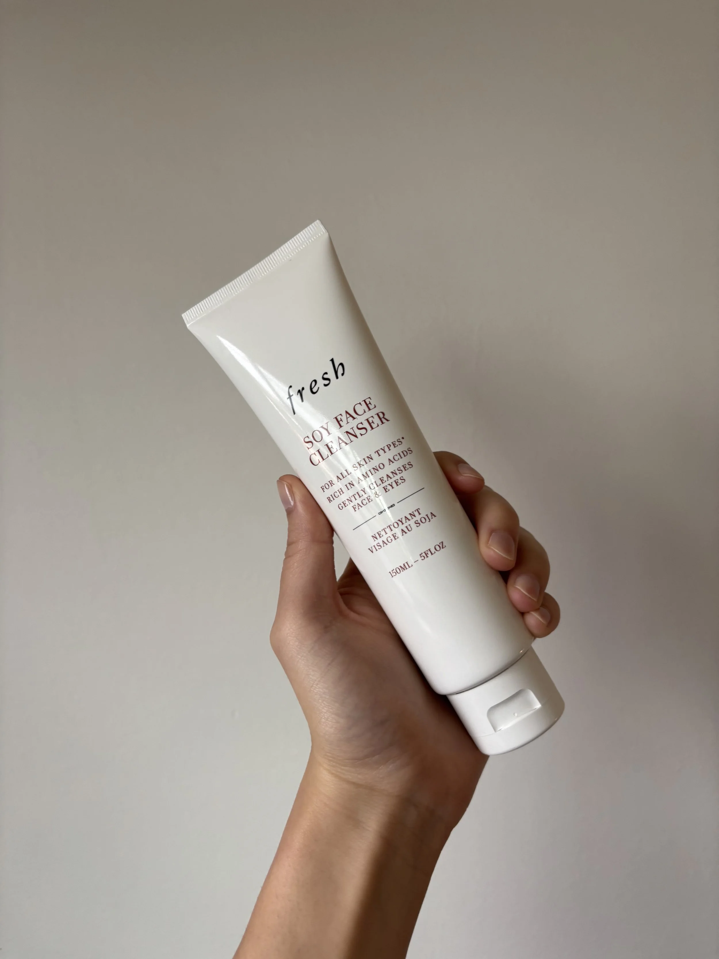 Hand holding up a large white bottle of fresh brand soy face cleanser