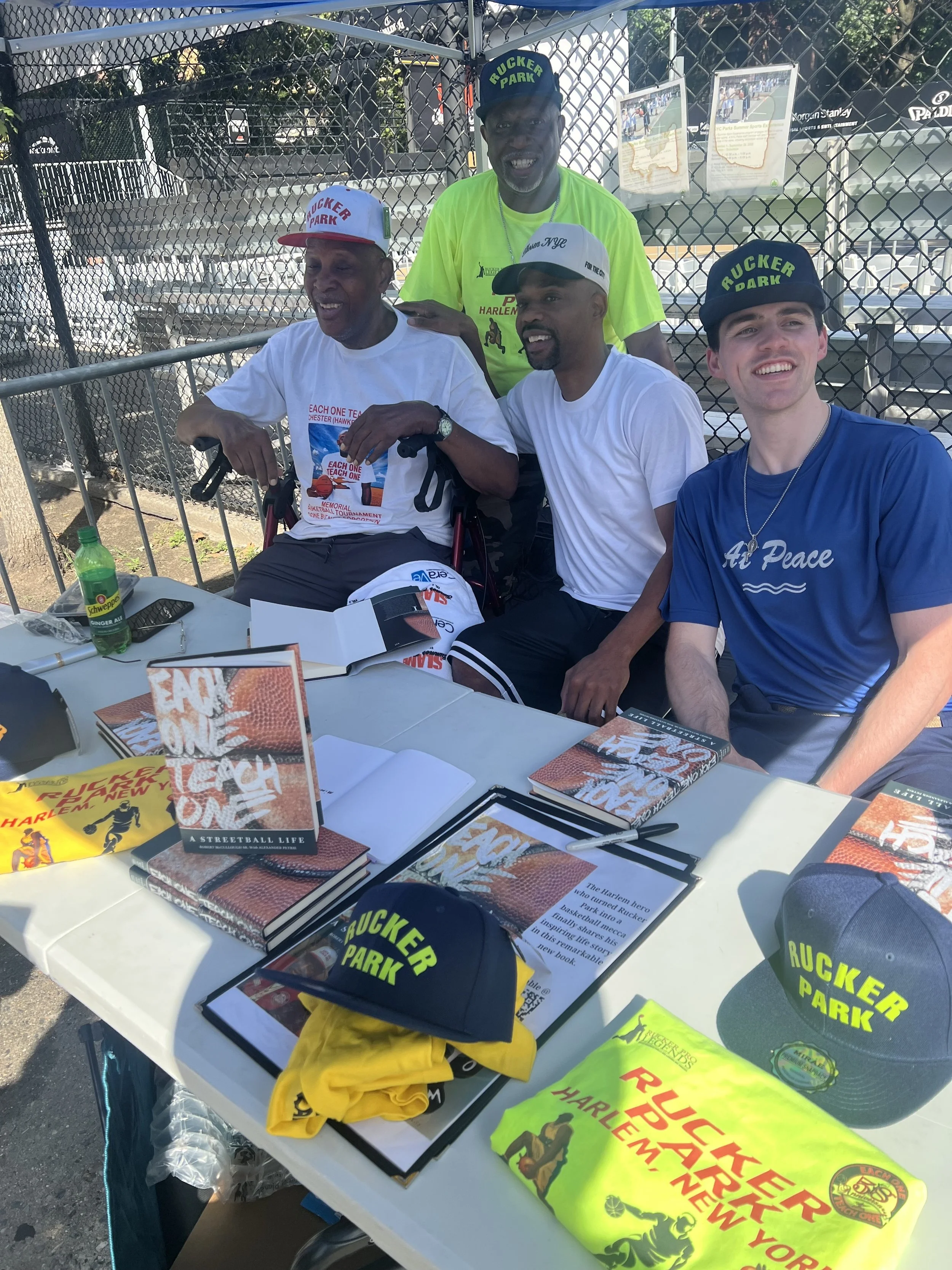 Photograph of the two coauthors with Rafer Alston at the Each One Teach One launch event in August 2026 at Rucker Park.