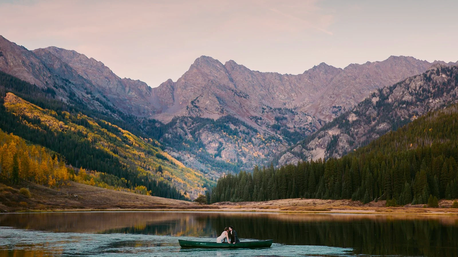 bride and groom at a mountain wedding in colorado in a canoe on a lake at sunset