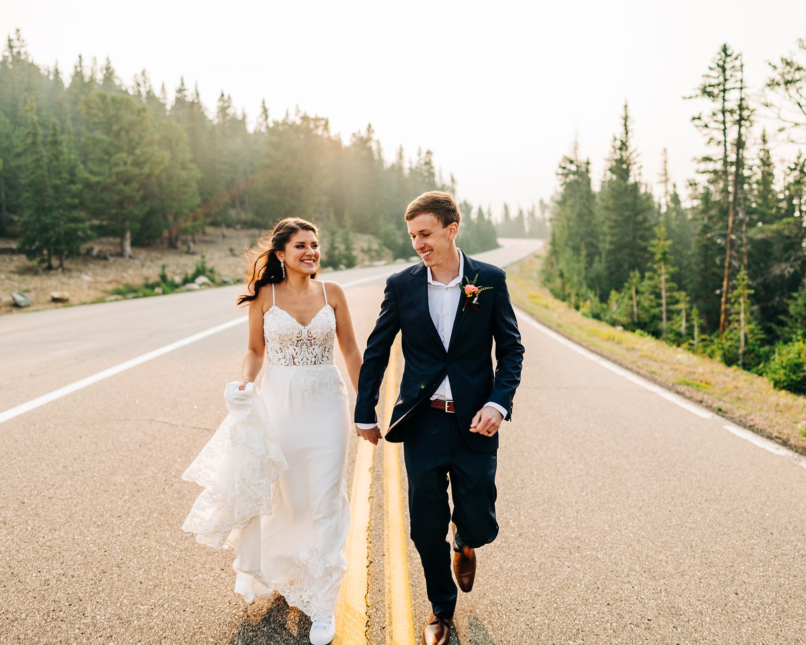 rocky mountain national park couple running down street after wedding at sunrise