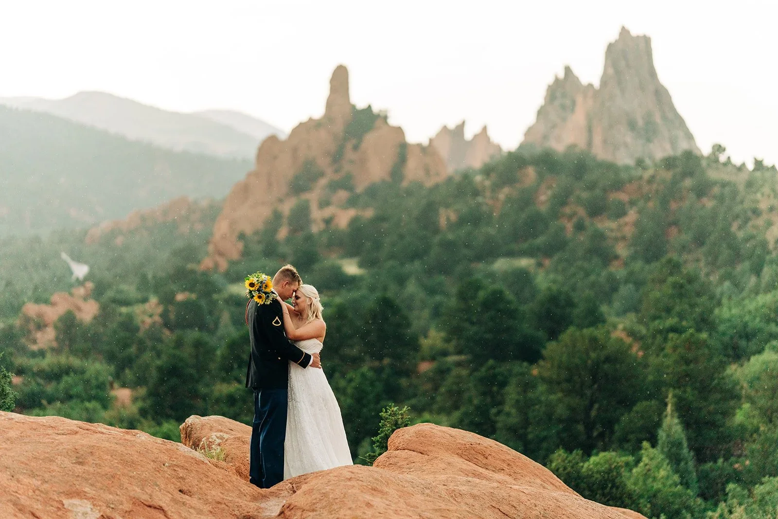 garden of the gods elopement wedding in colorado springs with bride and groom hugging after the ceremony and red rocks in background.