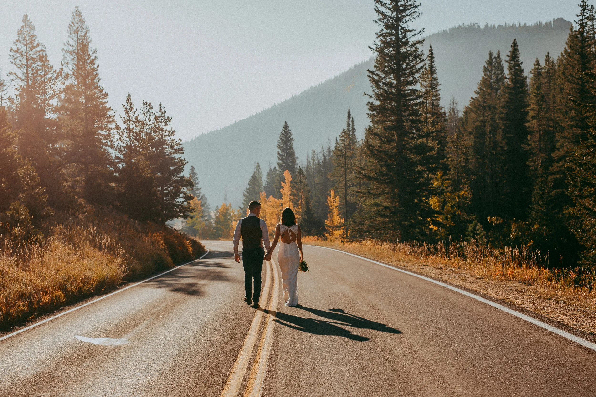 bride and groom walking down the road in rocky mountain national park after their elopement
