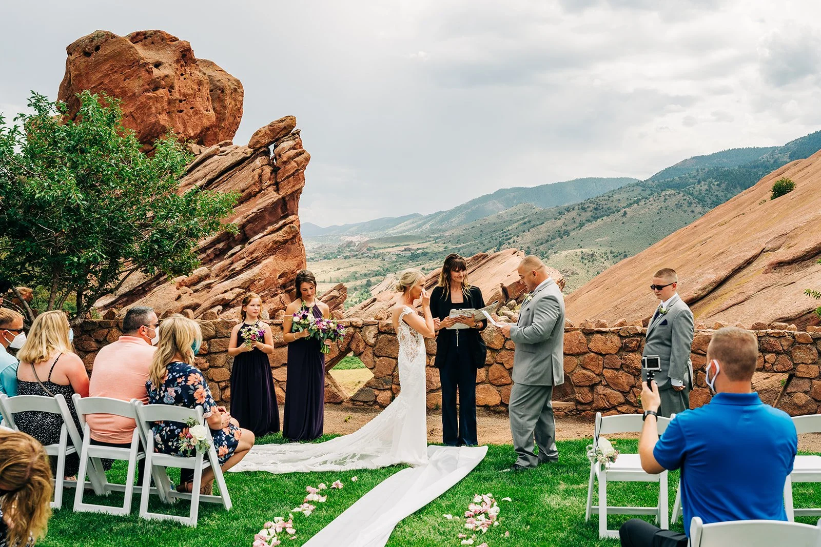 red rocks wedding outsdie denver with couple reading vows and officiant smiling