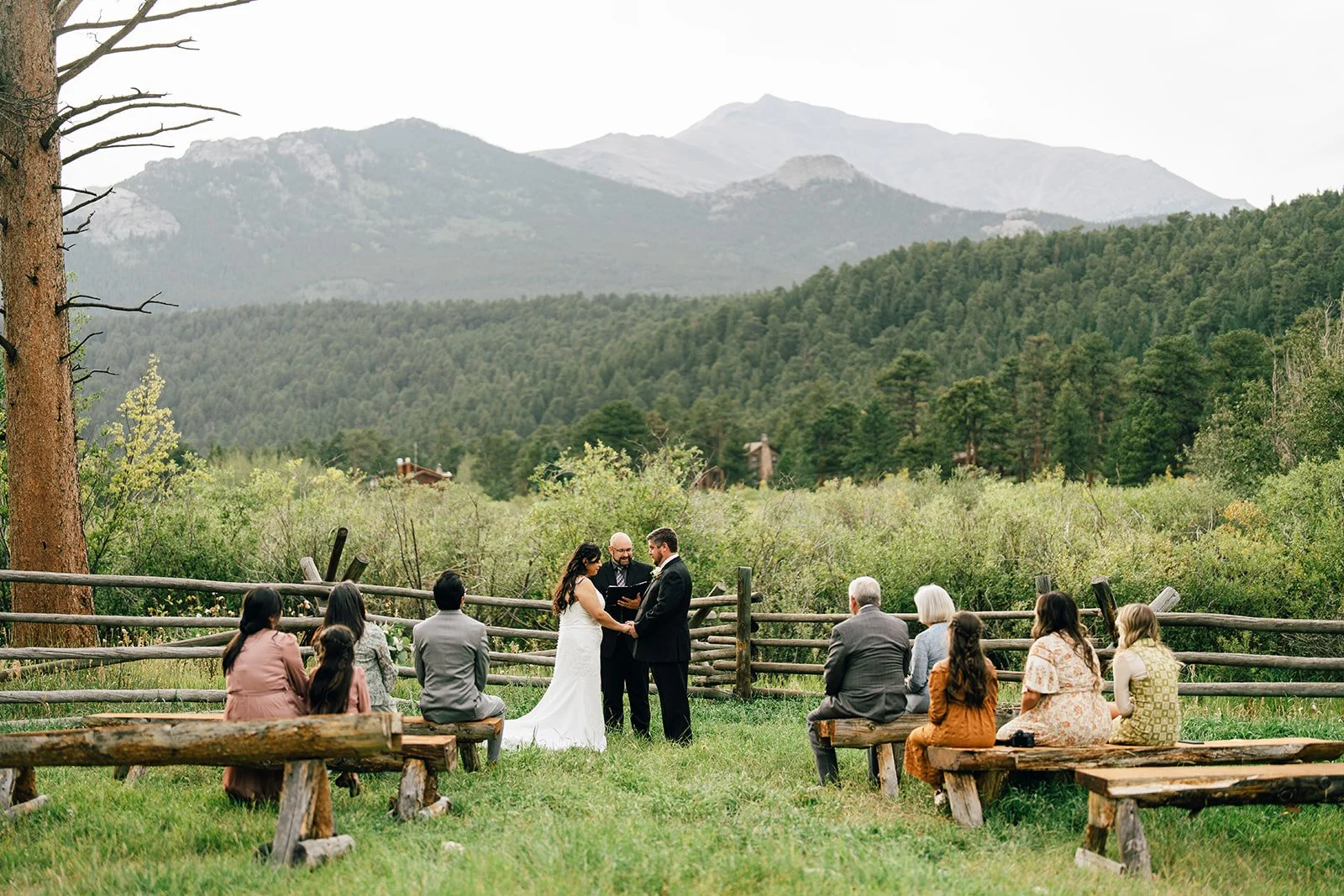 rocky mountain wedding and elopement park ceremony site near estes park colorado during a wedding ceremony with friends and family watching bride and groom exchange vows