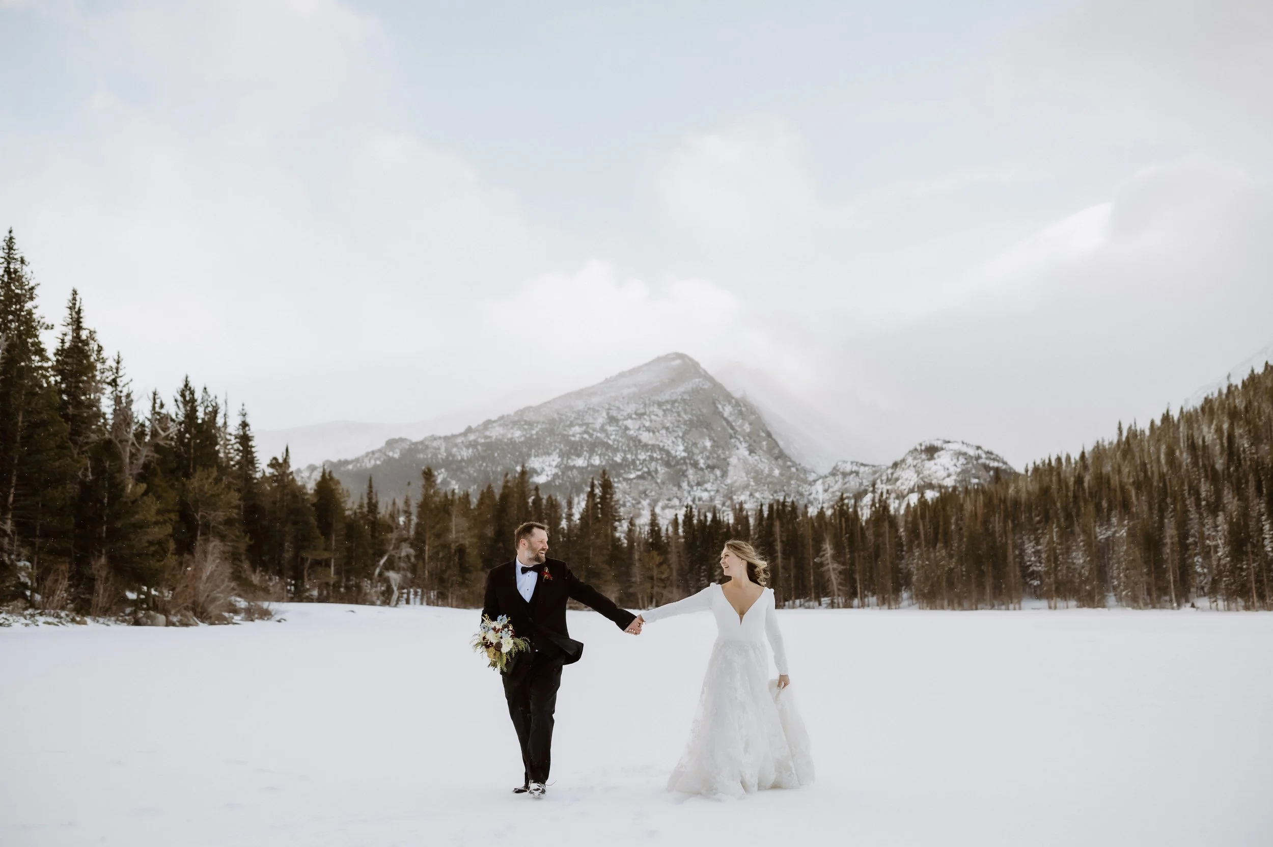 rocky mountain national park bear lake wedding ceremony site with couple walking in the snow after their ceremony
