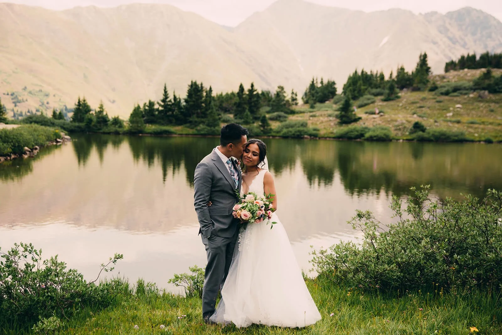 bride and groom taking portrait photos at pass lake near loveland pass in summit county colorado