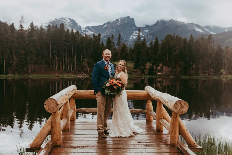 rocky mountain national park sprague lake wedding ceremony with bride posing with flowers and snow on mountain in background