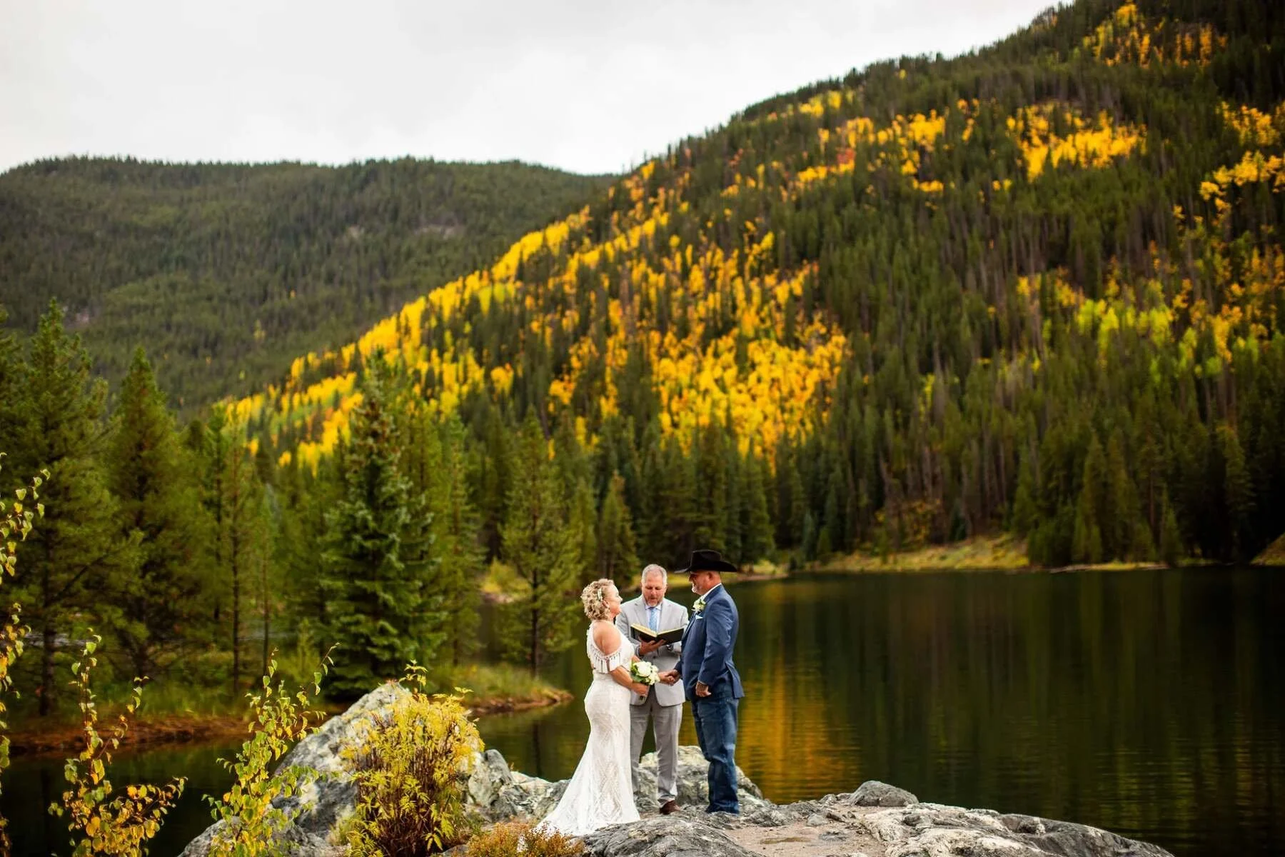 small wedding ceremony with bride and groom exchanging vows at officer's gulch near Frisco, Colorado. Fall colors with aspen trees changing in the background.