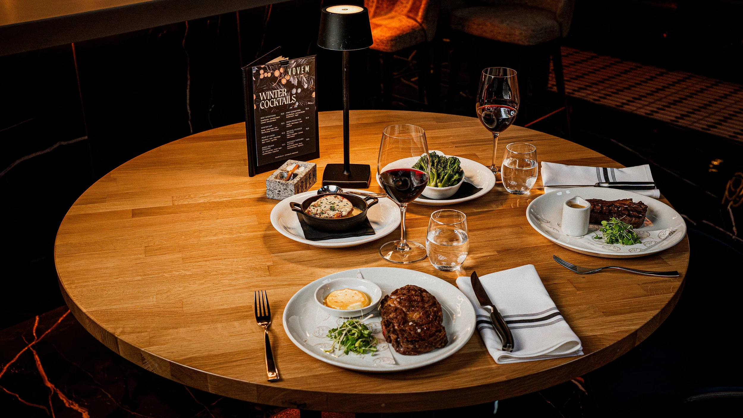 Image of Vovem round table set for the Steak Deal for Two offer, with two steaks and two sides.