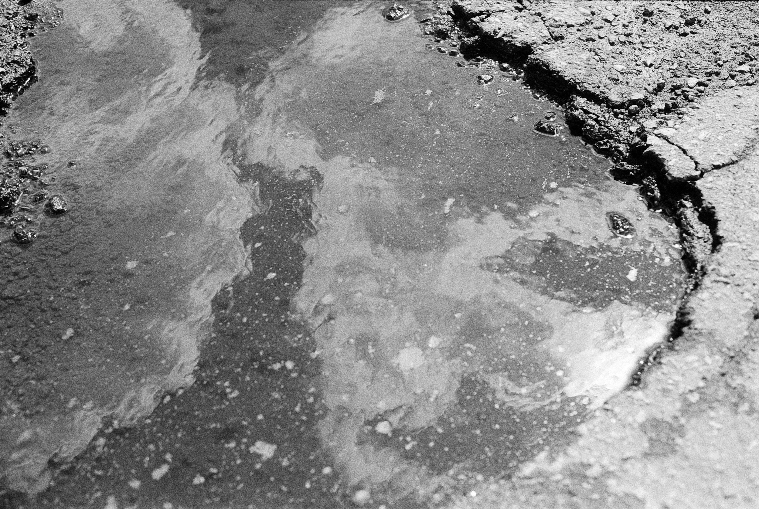 The softness of the clouds reflected in the dirty and broken asphalt.