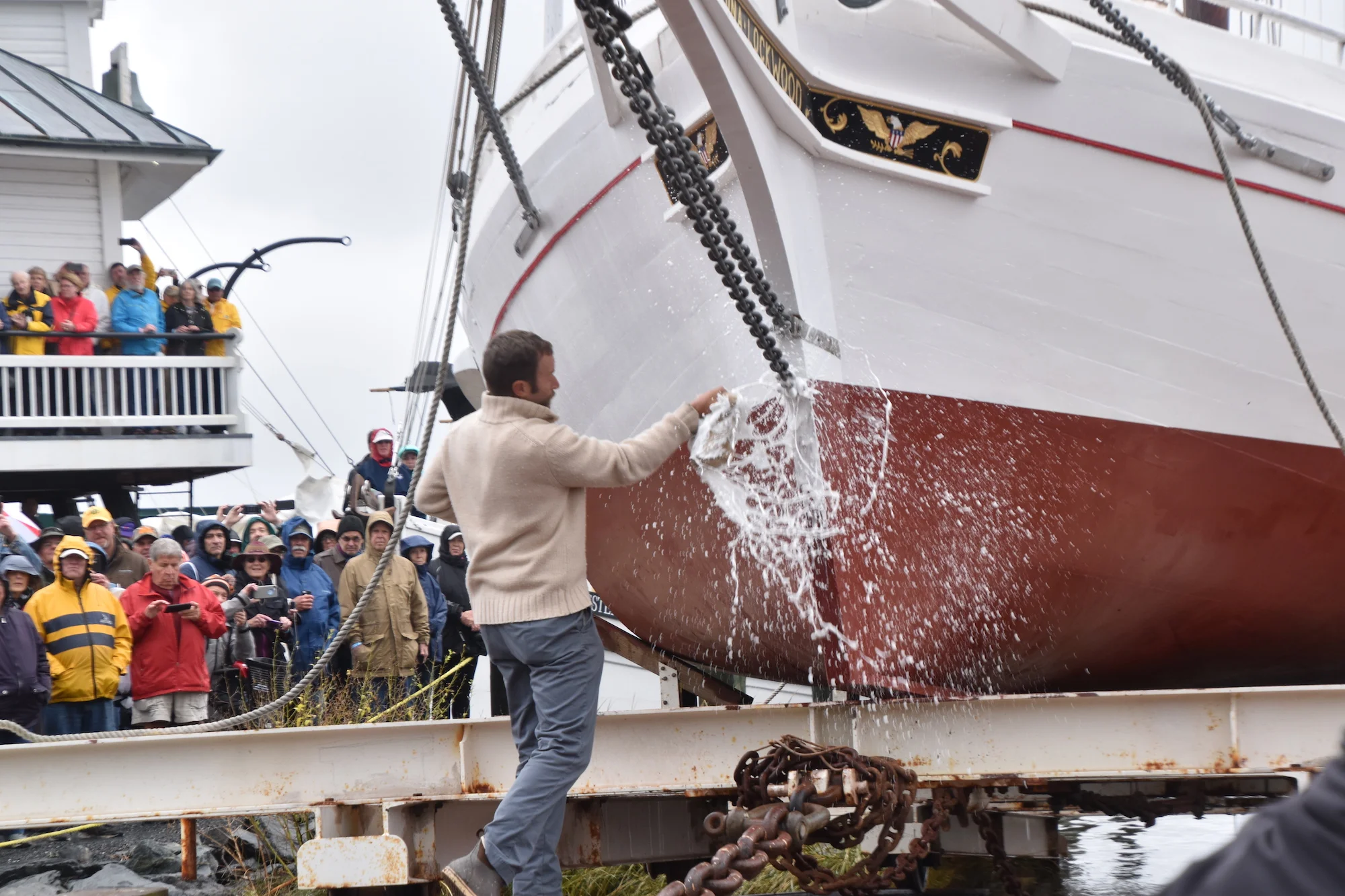 Shipwright Joe Connor smashes a bottle of champagne against the bow of 1889 bugeye Edna Lockwood to christen her before her return to the Miles River on Saturday, Oct. 27, 2018.