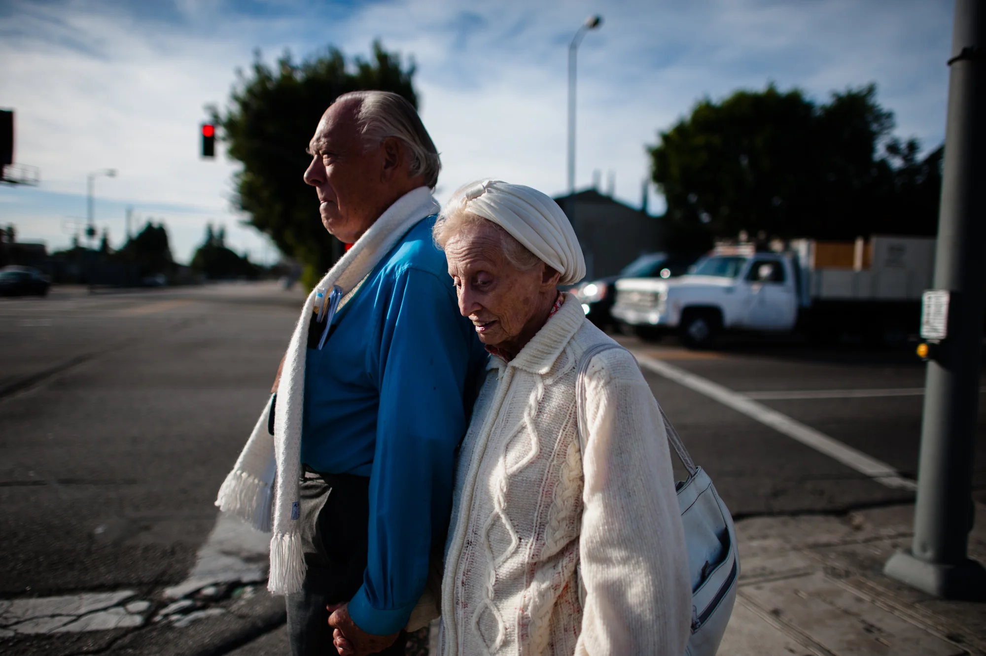 Adina holds Will’s hand as they stand on a street corner.