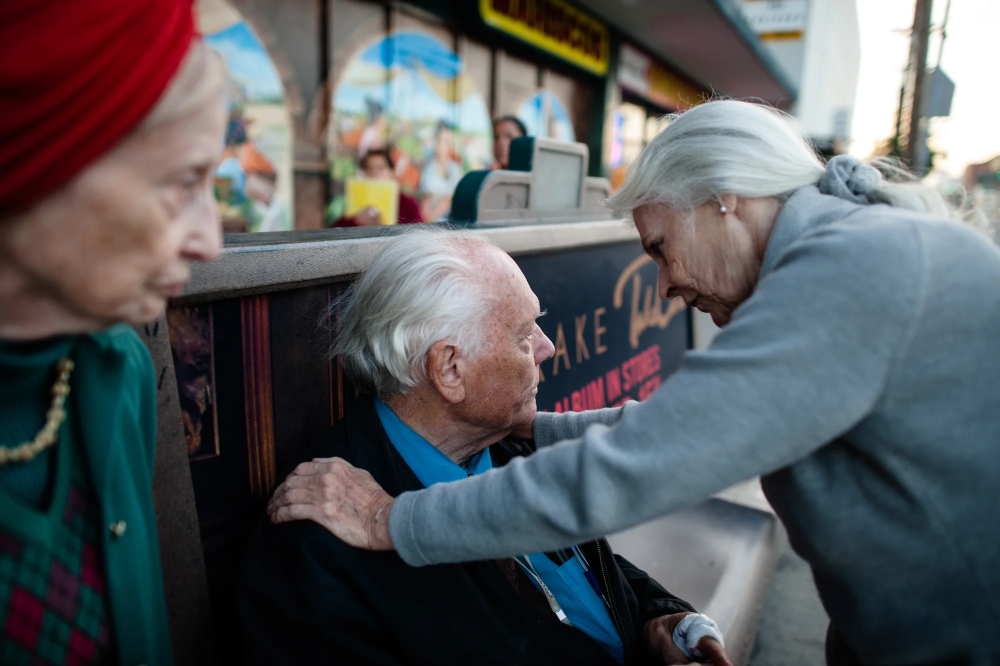 Jeanie places her hands on Will’s shoulders, as he sits at the bus station, while Adina stands with them.