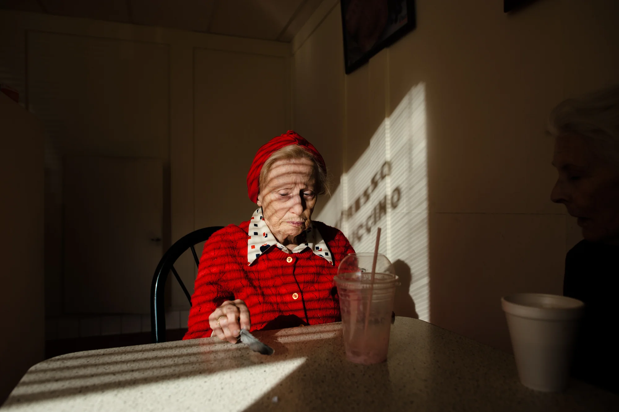 Adina holds a bird’s leaf she collected, as she sits with Jeanie at the donut shop.