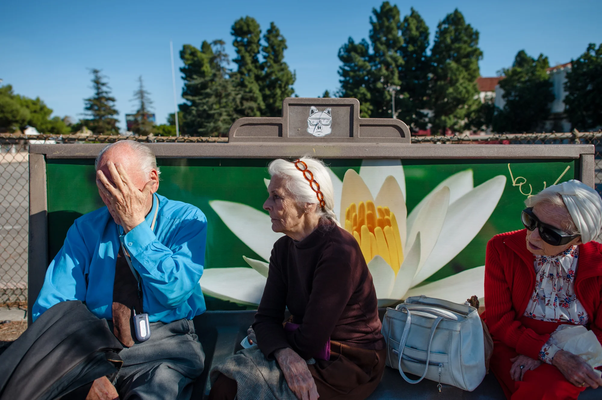 Will grips his face in frustration, as Jeanie and Adina look at him, while they sit at a bus stop, resting after a long walk.