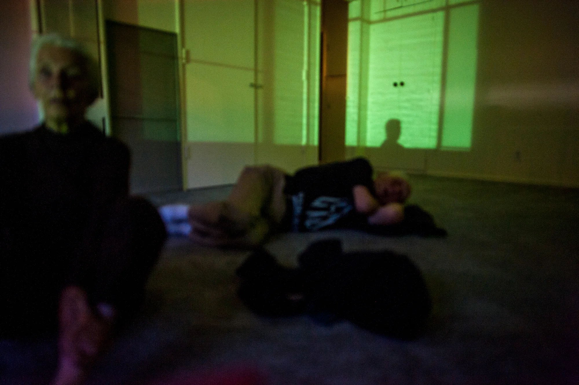 Will reclines on the floor of his studio apartment, as Jeanie sits beside him, at night.