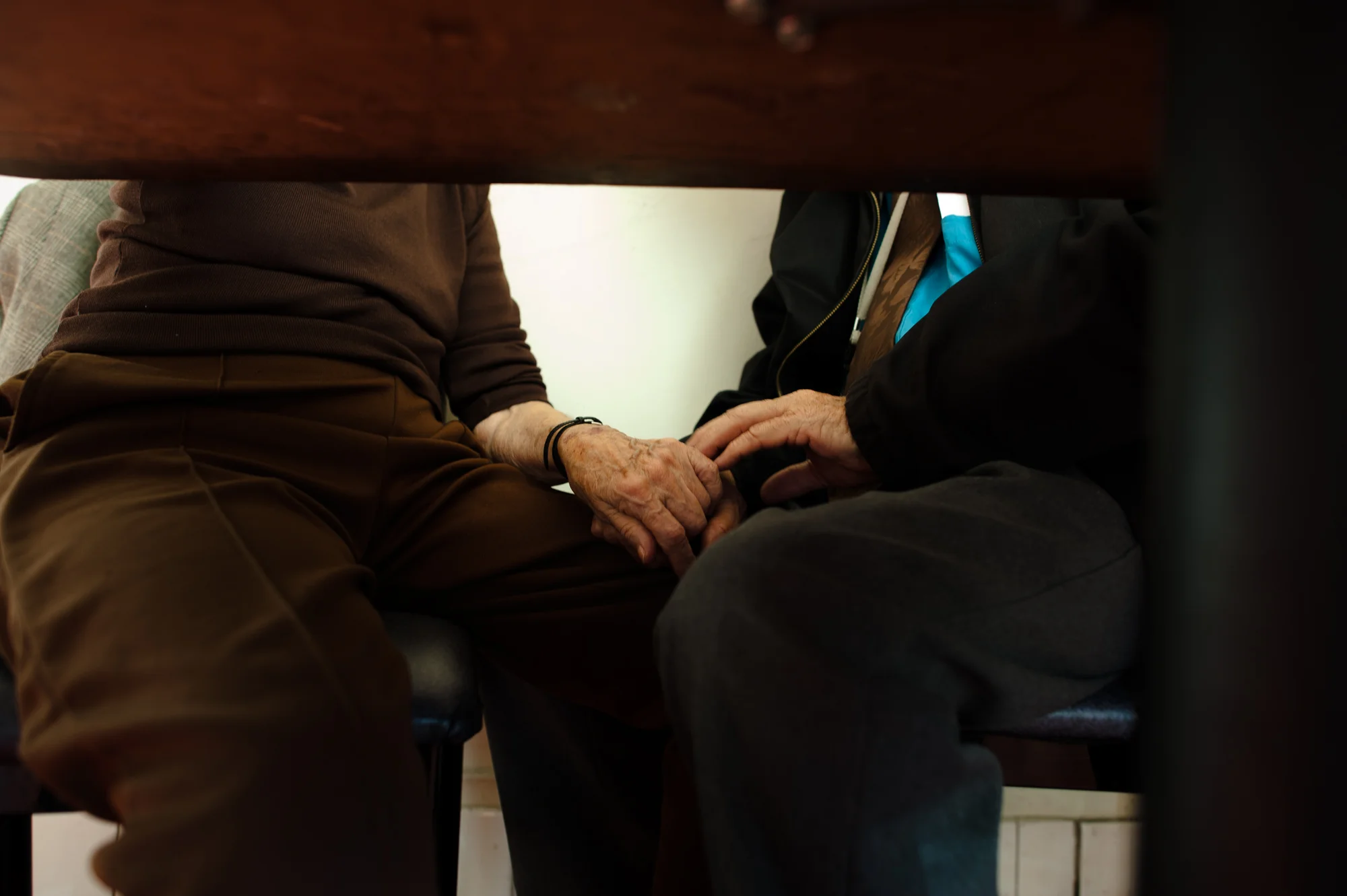 Will and Jeanie’s hands touch under a table.
